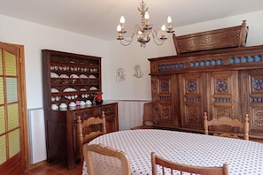 Ein Essbereich mit einem runden Tisch, Stühlen, einer Chandelieber und einem Holzschrank mit Verzierungen.