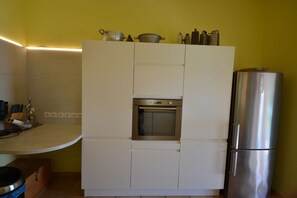 A compact kitchen with a built-in oven, a stainless steel refrigerator, and a countertop with kitchen utensils. - directly at the stand (Solenzara)