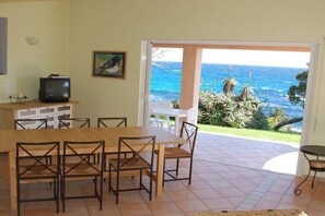 A dining area with a view of the ocean, a television, and a painting on the wall. - directly at the stand (Solenzara)