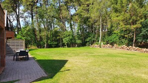Un jardin avec un espace patio, une clôture en bois et un mur en pierre.
