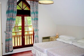 A bedroom with a bed, a nightstand, a lamp, and a window with curtains. - Les Jumeaux -Le Touquet -Families - V.Close Golf (Le Touquet)