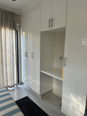 Una habitación con un armario grande, una cama con ropa de cama a rayas y una alfombra negra.