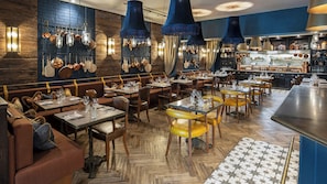 A restaurant interior with wooden flooring, multiple seating areas, and hanging light fixtures. - CBH Beadnell Towers & Kitchen (Chathill)