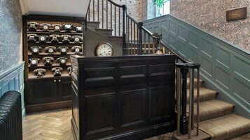 A staircase with a wooden handrail and a wall-mounted clock.