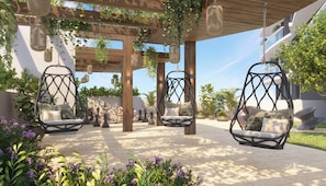Un espace extérieur aménagé, abrité et doté de chaises suspendues et de jardinières.