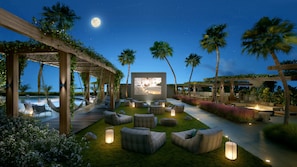 A nighttime outdoor lounge area with a pool, seating, and a large screen displaying a scene. - High Floor Signature Suite | Brand New | Resort Pool + Gym | Nexo Miami (North Miami Beach)