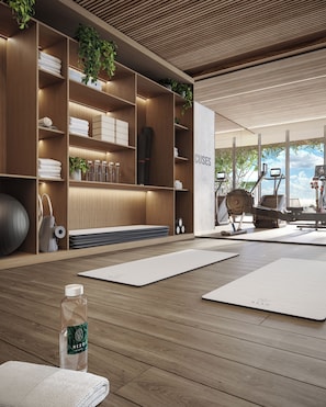 A modern wellness room with wooden shelving, yoga mats, and exercise equipment. - High Floor Signature Suite | Brand New | Resort Pool + Gym | Nexo Miami (North Miami Beach)
