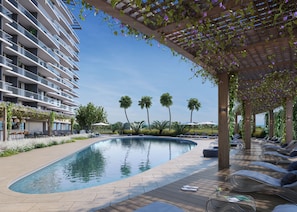 A swimming pool with a wooden deck, lounge chairs, and a covered area with plants. - Grand Residence | Rooftop Dining + Resort Pool + Spa | Near Beach | Nexo Miami (North Miami Beach)