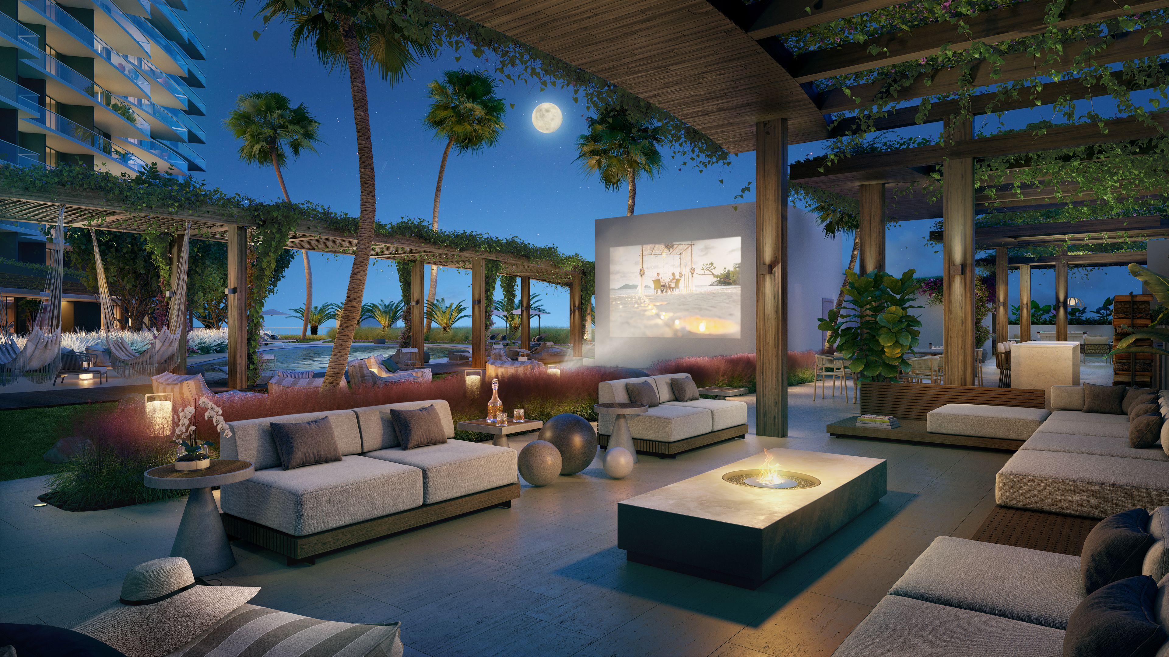 A modern outdoor lounge area with seating, a fire feature, and a view of a pool and palm trees.