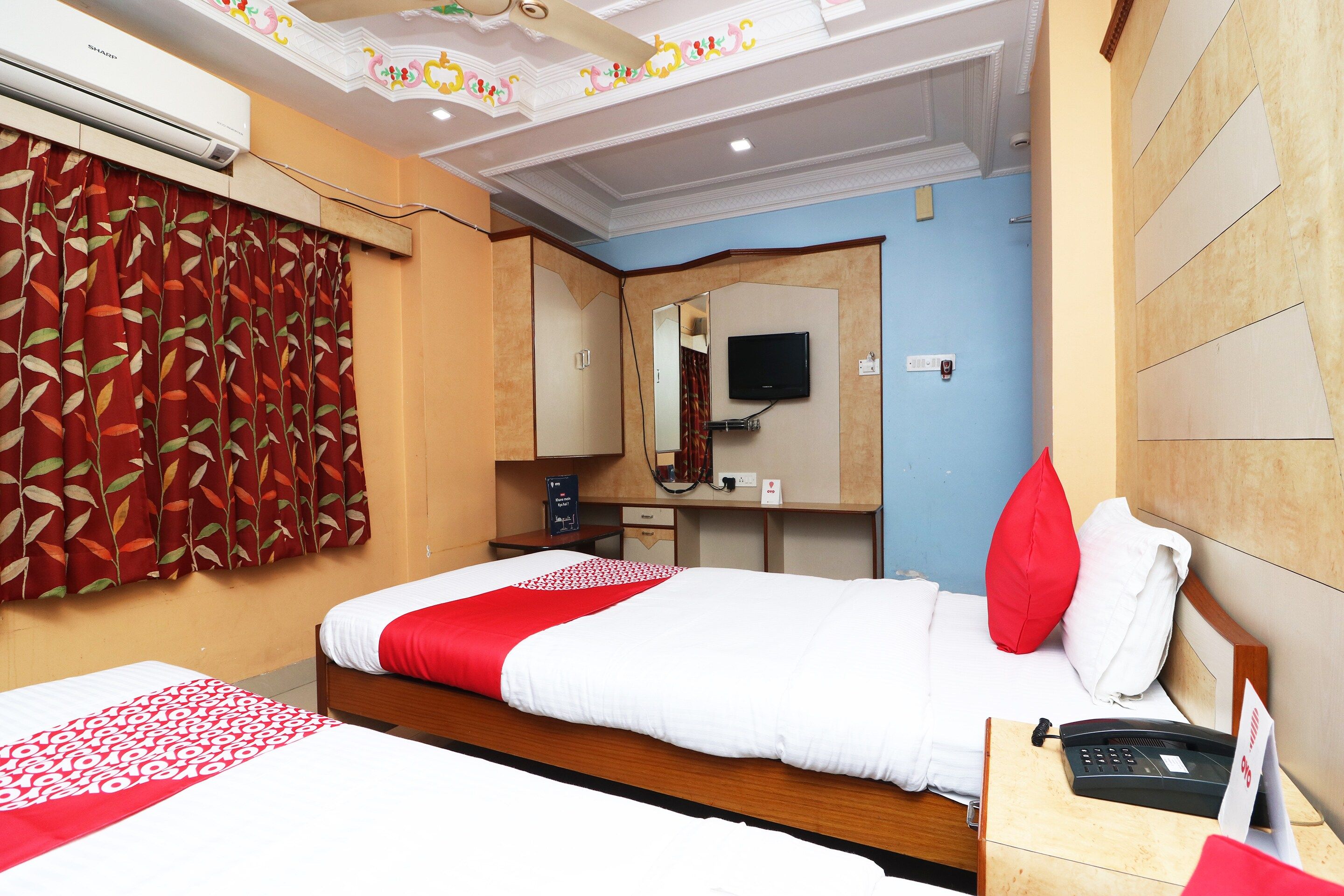 Una habitación de hotel con una cama, un escritorio con teléfono y una televisión montada en la pared.