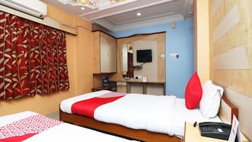 Una habitación de hotel con una cama, un escritorio con teléfono y una televisión montada en la pared.