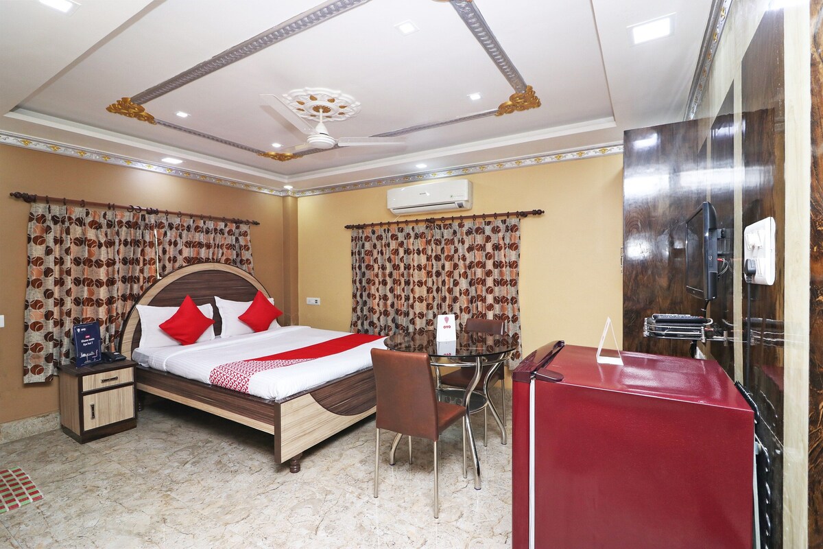Habitación de hotel con cama, mesita de noche, silla, escritorio y aire acondicionado.