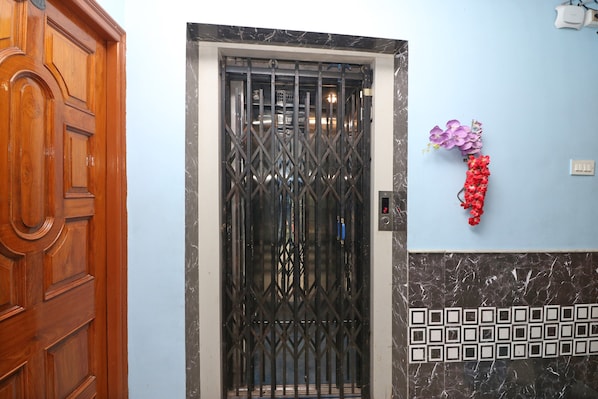Una puerta de madera, un portón de metal y una pared con un interruptor de luz y flores decorativas.