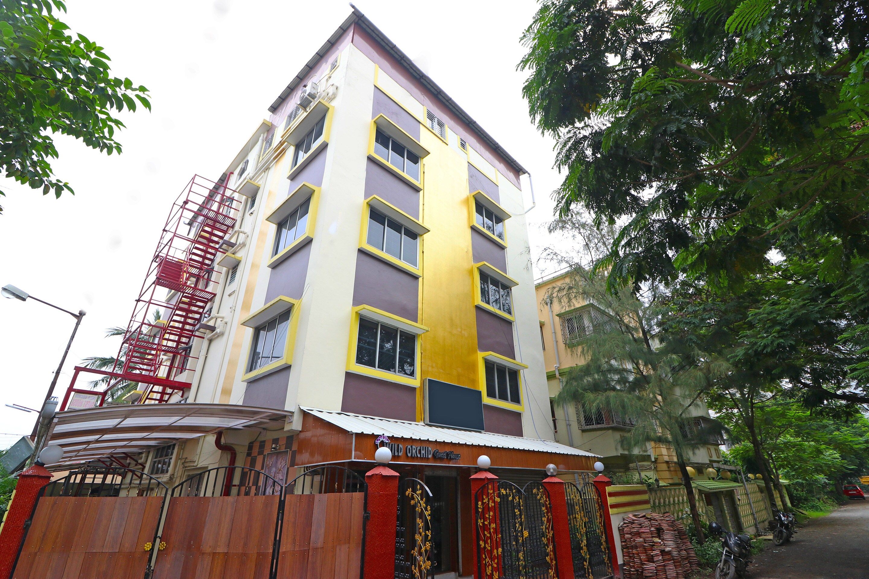 Un edificio de varios pisos con fachada roja y amarilla, una escalera visible y una entrada con reja.