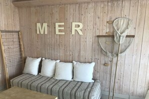 A room with a wooden wall, a bed with striped bedding, and a large 'MER' sign. - Les Mouettes just 50 m from the sea (Plouescat)