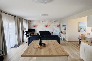 A modern living room with a wooden coffee table, a sofa, and a dining area with a table and chairs. - Les Mouettes just 50 m from the sea (Plouescat)