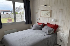 A bedroom with a bed, a bedside table, a nightstand, a window, and a view of the outside. - Les Mouettes just 50 m from the sea (Plouescat)