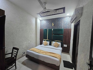 A hotel room with a bed, a chair, a ceiling fan, and an air conditioning unit. - Hotel O kaven grand (Amritsar)