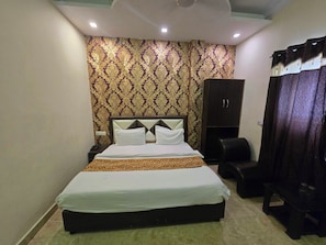 A neatly made bed with a headboard, a wardrobe, and a bench in a room with patterned wallpaper. - Hotel O kaven grand (Amritsar)