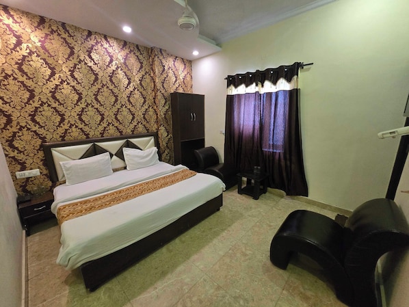 A hotel room with a bed, a wardrobe, a small table, and a chair. - Hotel O kaven grand (Amritsar)