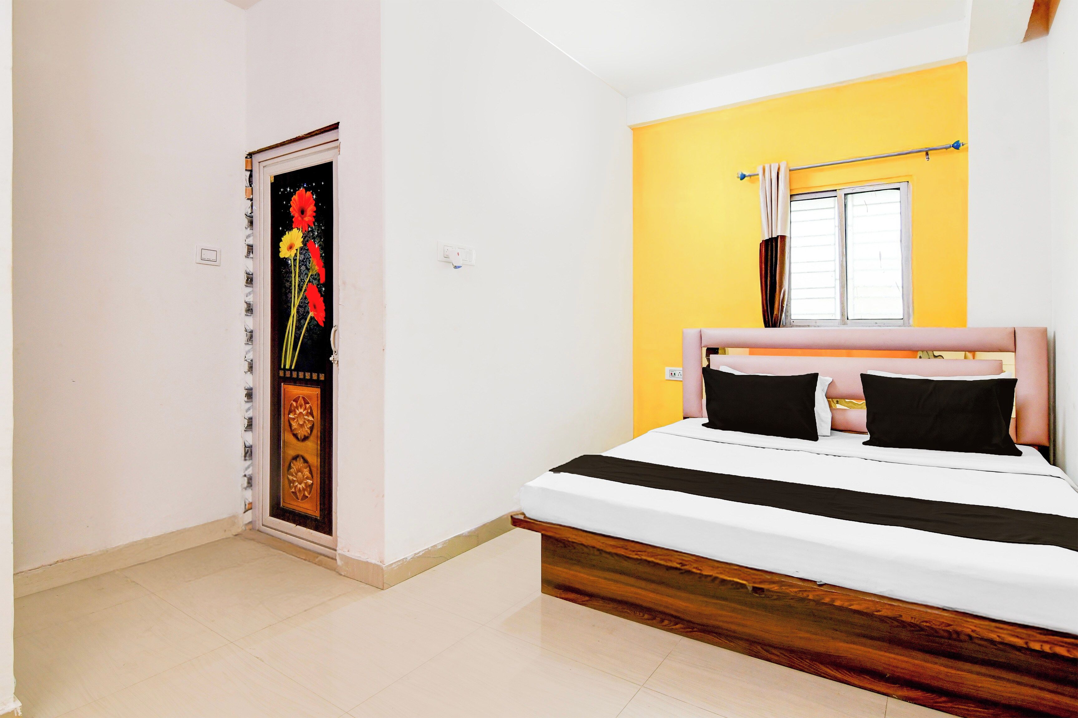 A bedroom with a bed, a door with a poster, a window, and a yellow wall.