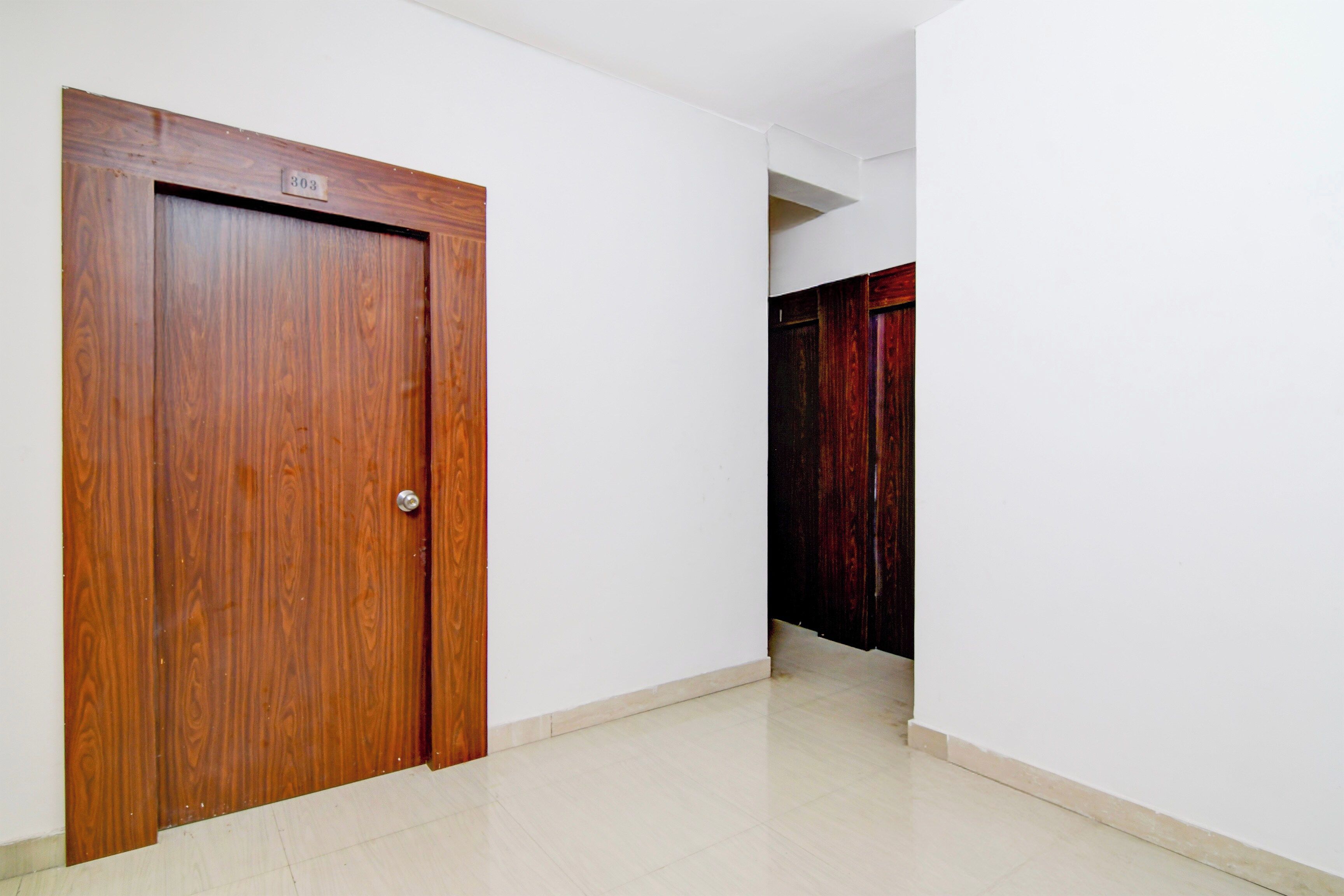 Un pasillo con una puerta de madera y una cortina roja.