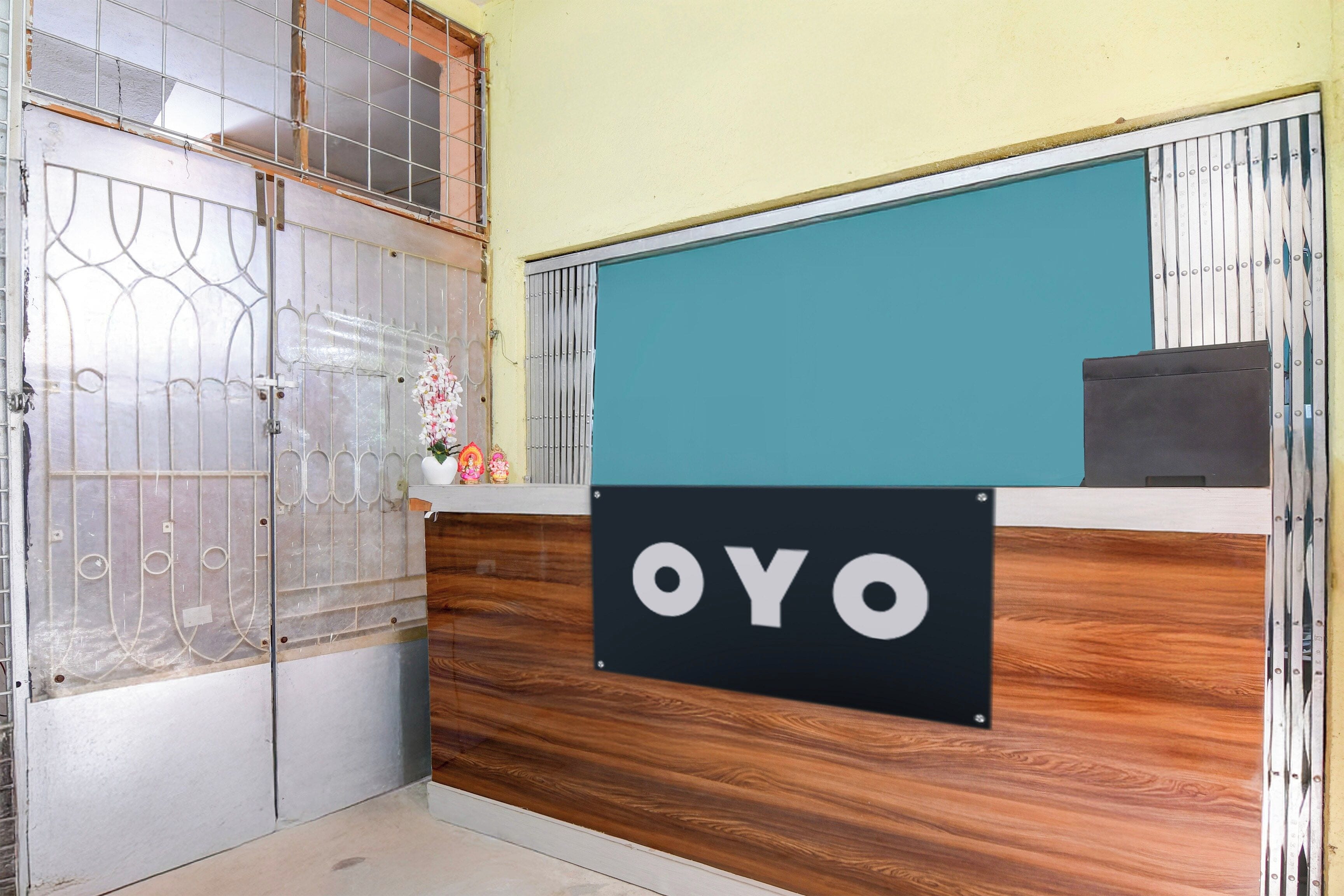 En receptionsdisk med en skylt som visar texten ”OYO” och en dekorativ blomsterarrangemang.