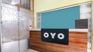 En receptionsdisk med en skylt som visar texten ”OYO” och en dekorativ blomsterarrangemang.