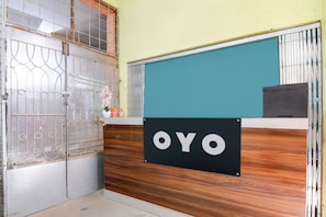 En receptionsdisk med en skylt som visar texten ”OYO” och en dekorativ blomsterarrangemang.