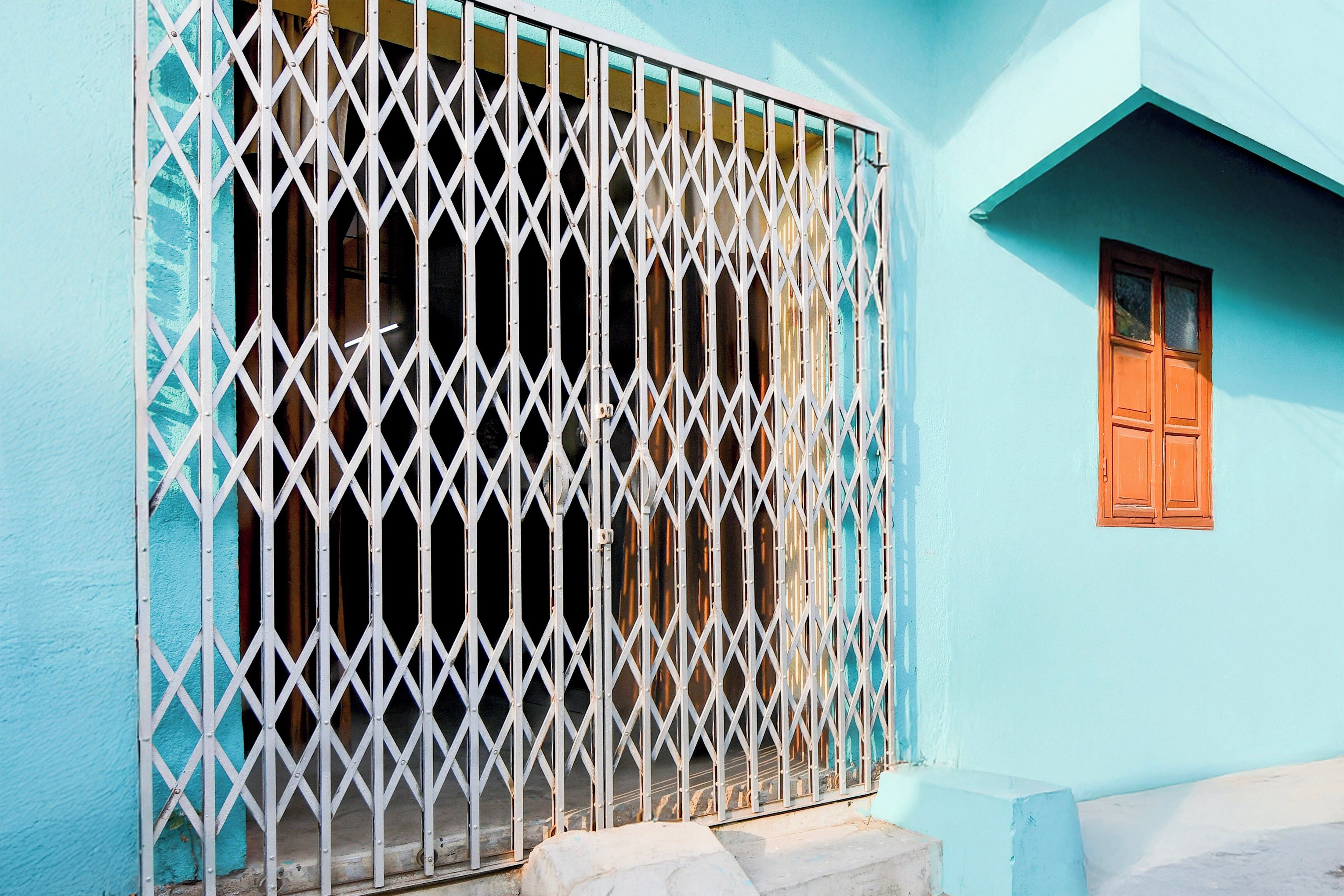 A building with a blue exterior, a barred window, and a wooden door.