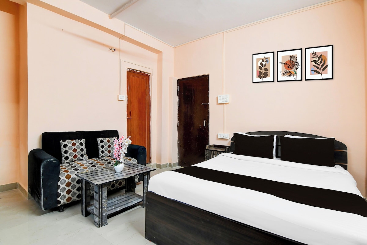 A hotel room with a bed, a sofa, a small table, and a wall-mounted TV.