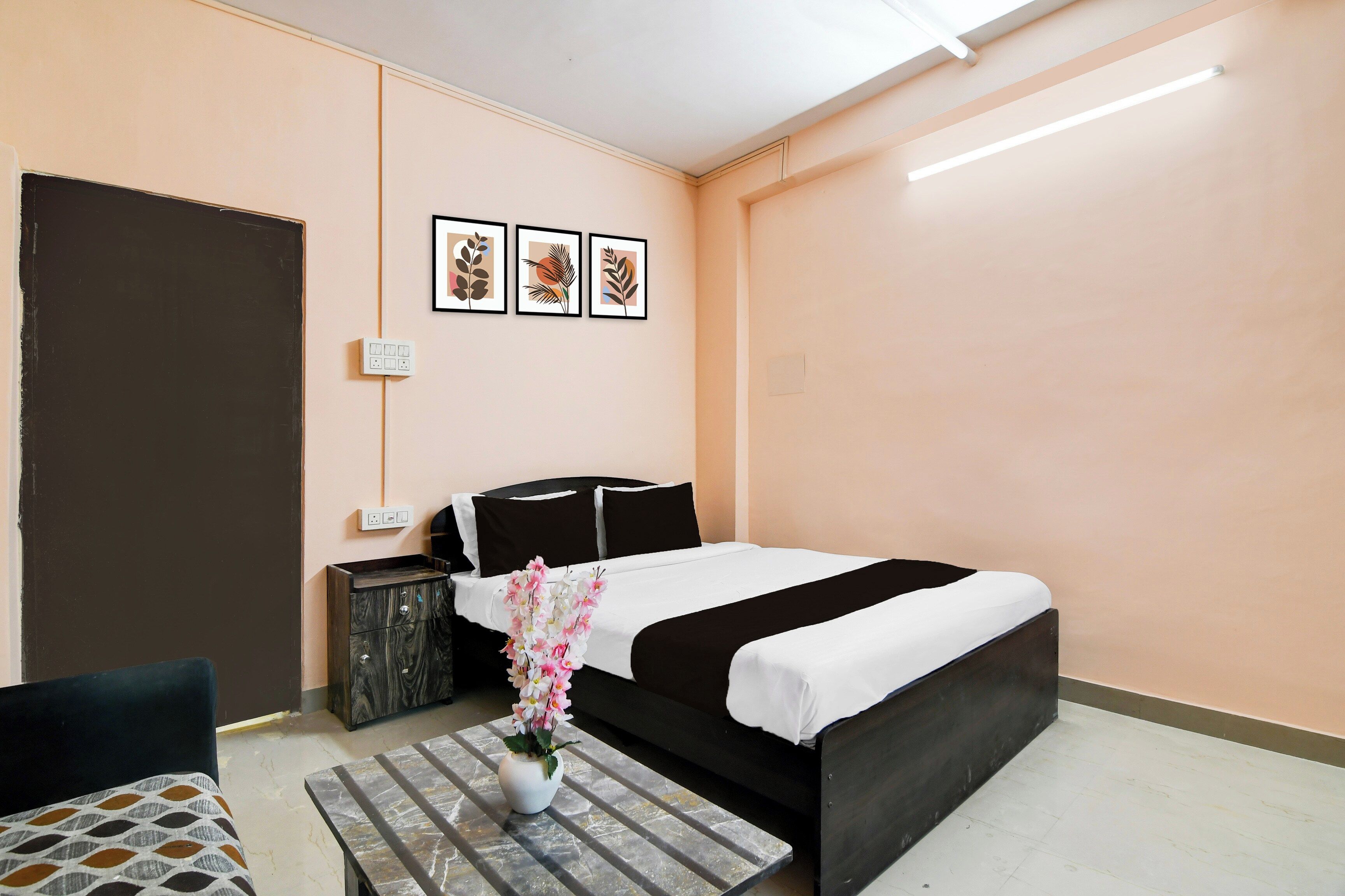Une chambre d’hôtel avec un lit, une table de chevet, une chaise et un vase avec des fleurs.