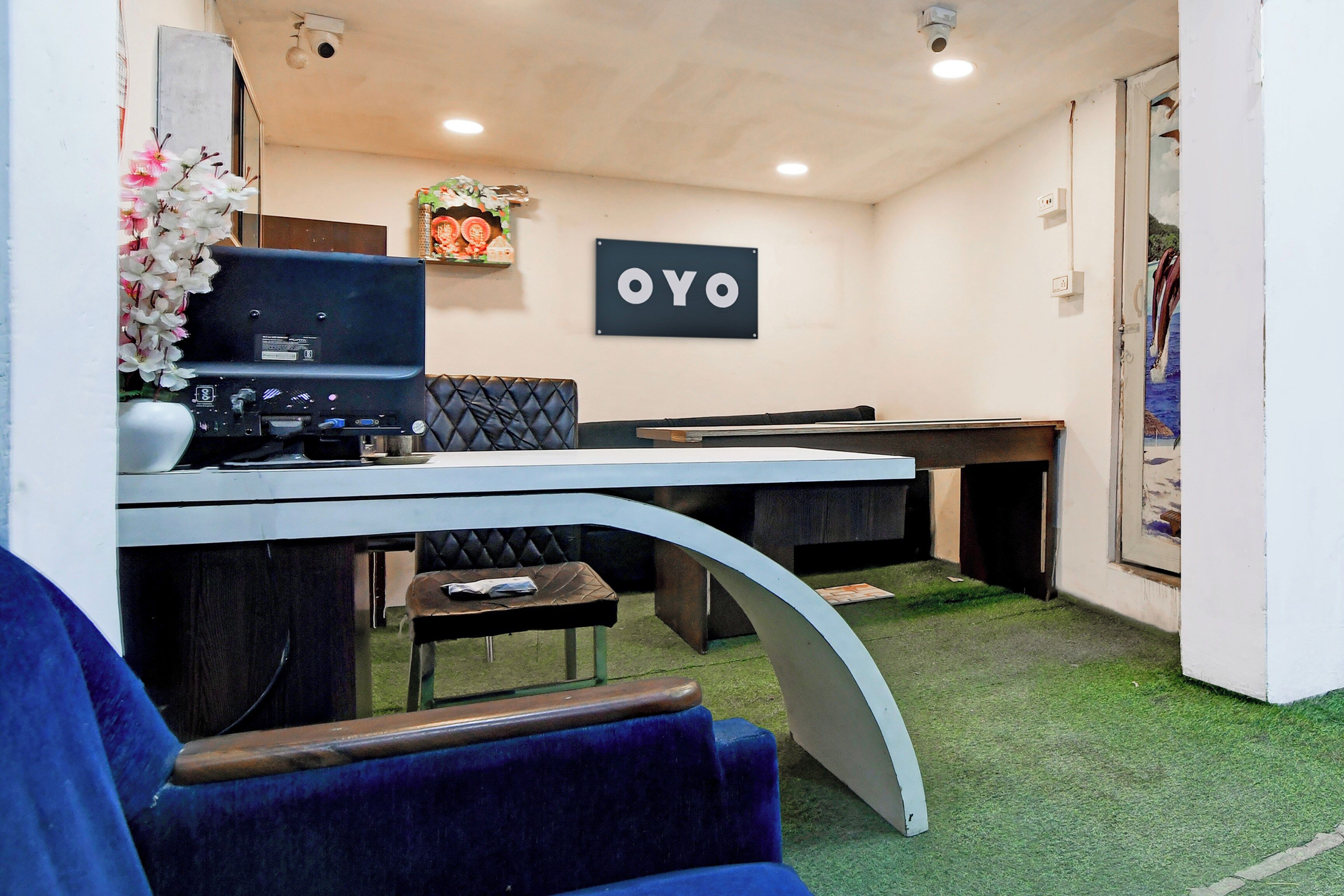 A reception area with a desk, a computer, a sign that reads 'OYO', and a painting on the wall.