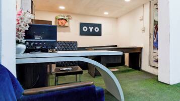 A reception area with a desk, a computer, a sign that reads 'OYO', and a painting on the wall.