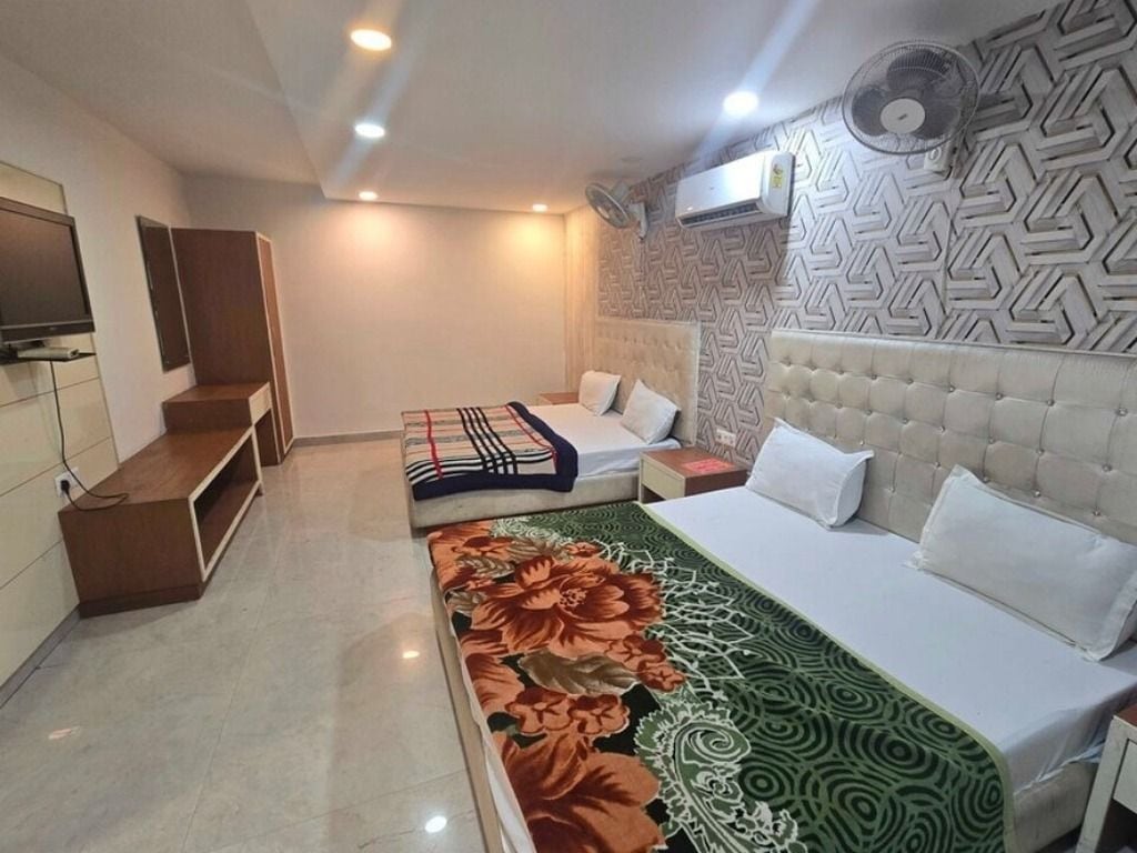A hotel room with a bed, a sofa, a TV, and a patterned wall.