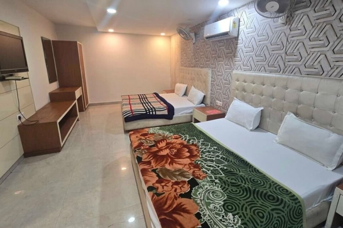 A hotel room with a bed, a sofa, a TV, and a patterned wall.