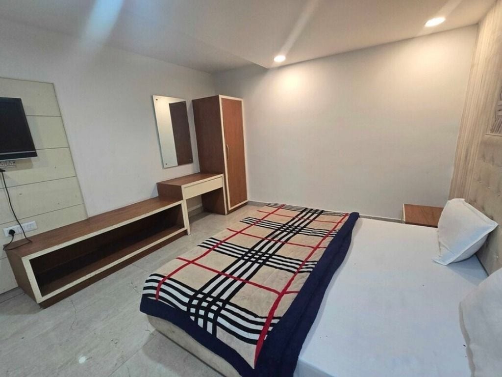 A bedroom with a bed, a bench, a TV, and a mirror.