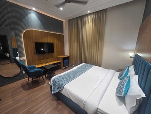 A hotel room with a bed, a desk, a chair, a television, and a curtain. - Hotel O Regal (Amritsar)
