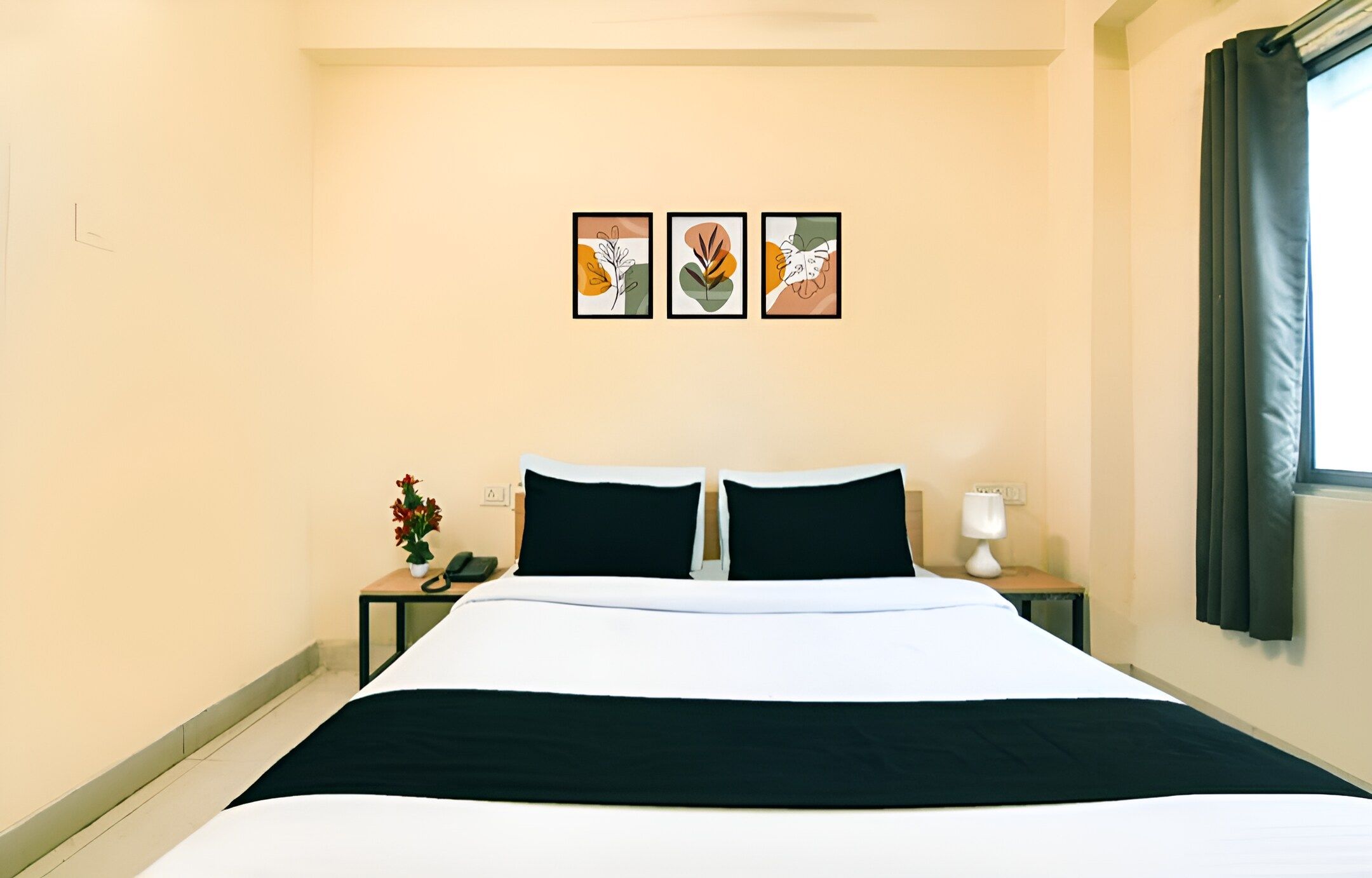 Habitación de hotel con cama, dos mesitas de noche, una lámpara y tres obras de arte enmarcadas en la pared.
