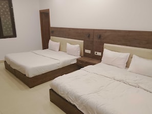 Ein Hotelzimmer mit zwei Betten, einem Holzkopfende und einem Nachttisch mit Schublade.
