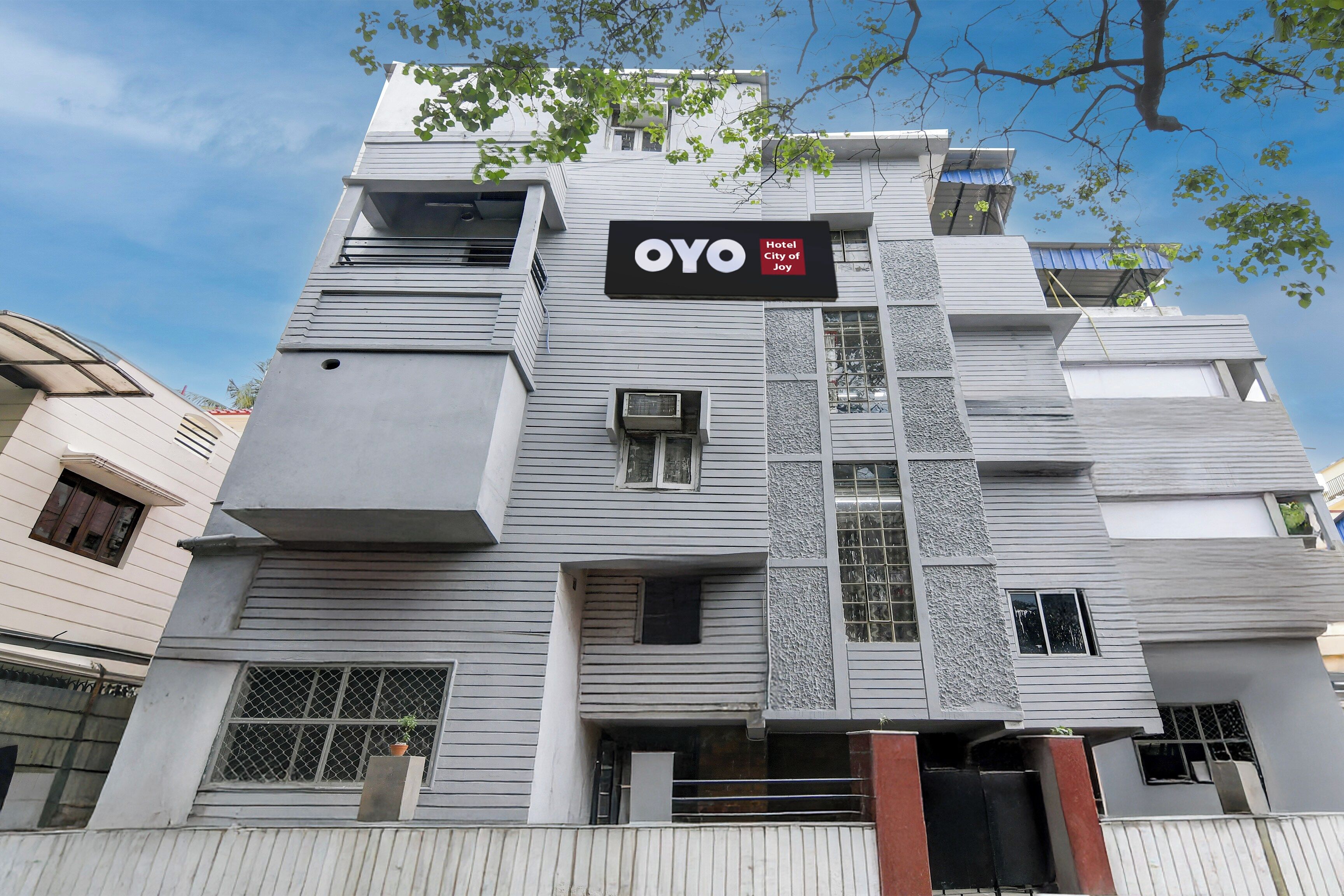 A modern hotel building with a prominent sign reading 'OYO Hotel City of Joy'.