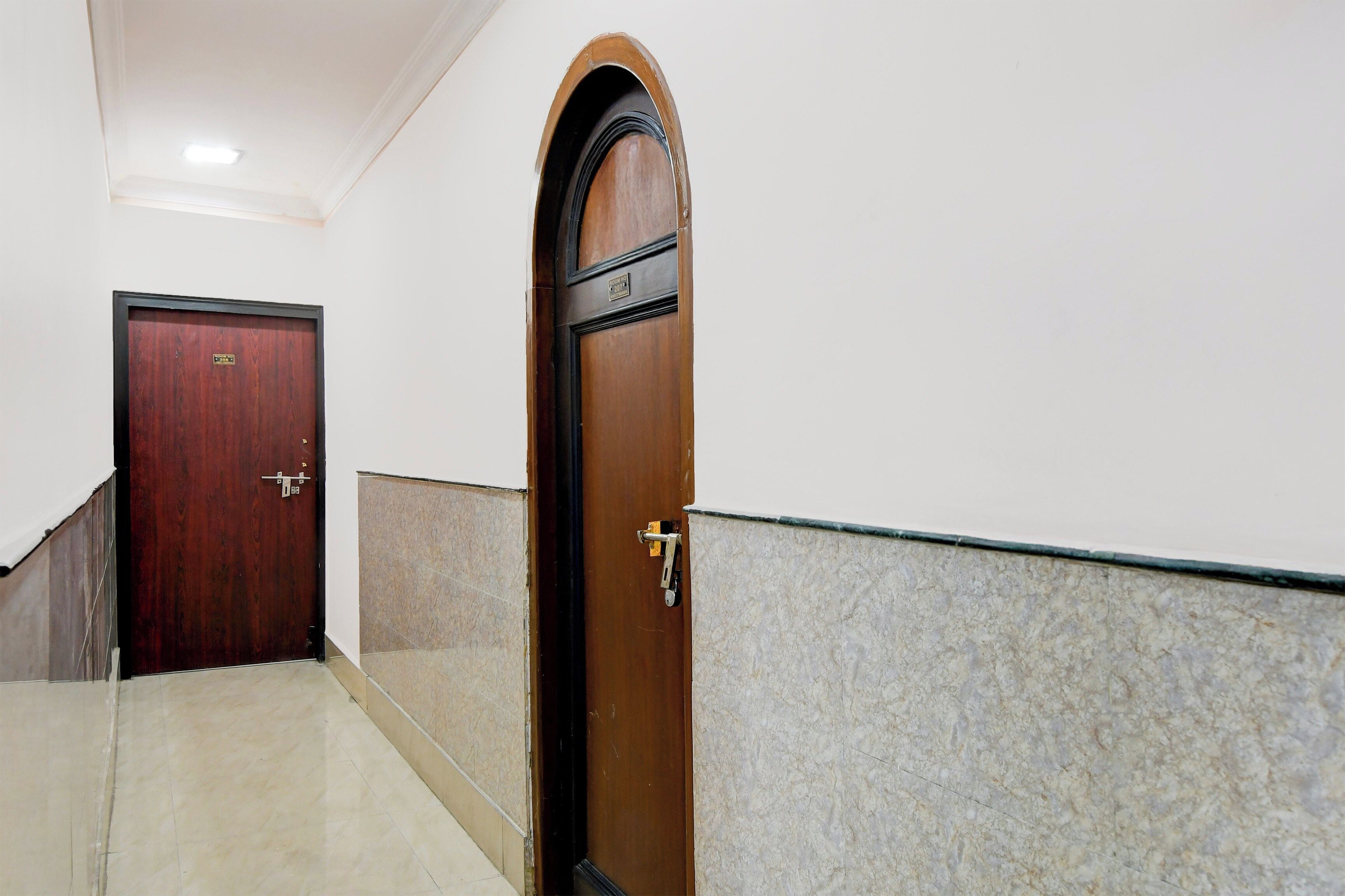 A hallway with a wooden door and a marble wall.