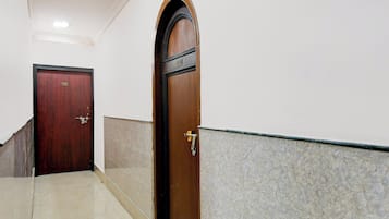 A hallway with a wooden door and a marble wall.