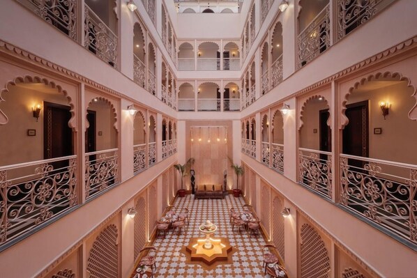 A multi-level hotel lobby with ornate railings, a central seating area, and a patterned floor. - Justa Ssatvsa Resort & Spa Udaipur (Udaipur)
