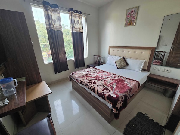 A bedroom with a bed, bedside table, and a window with curtains. - Hotel O The fortune grand (Amritsar)