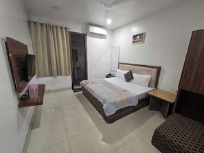 A hotel room with a bed, bedside table, TV, air conditioning unit, and a bathroom visible through an open door. - Hotel O The fortune grand (Amritsar)