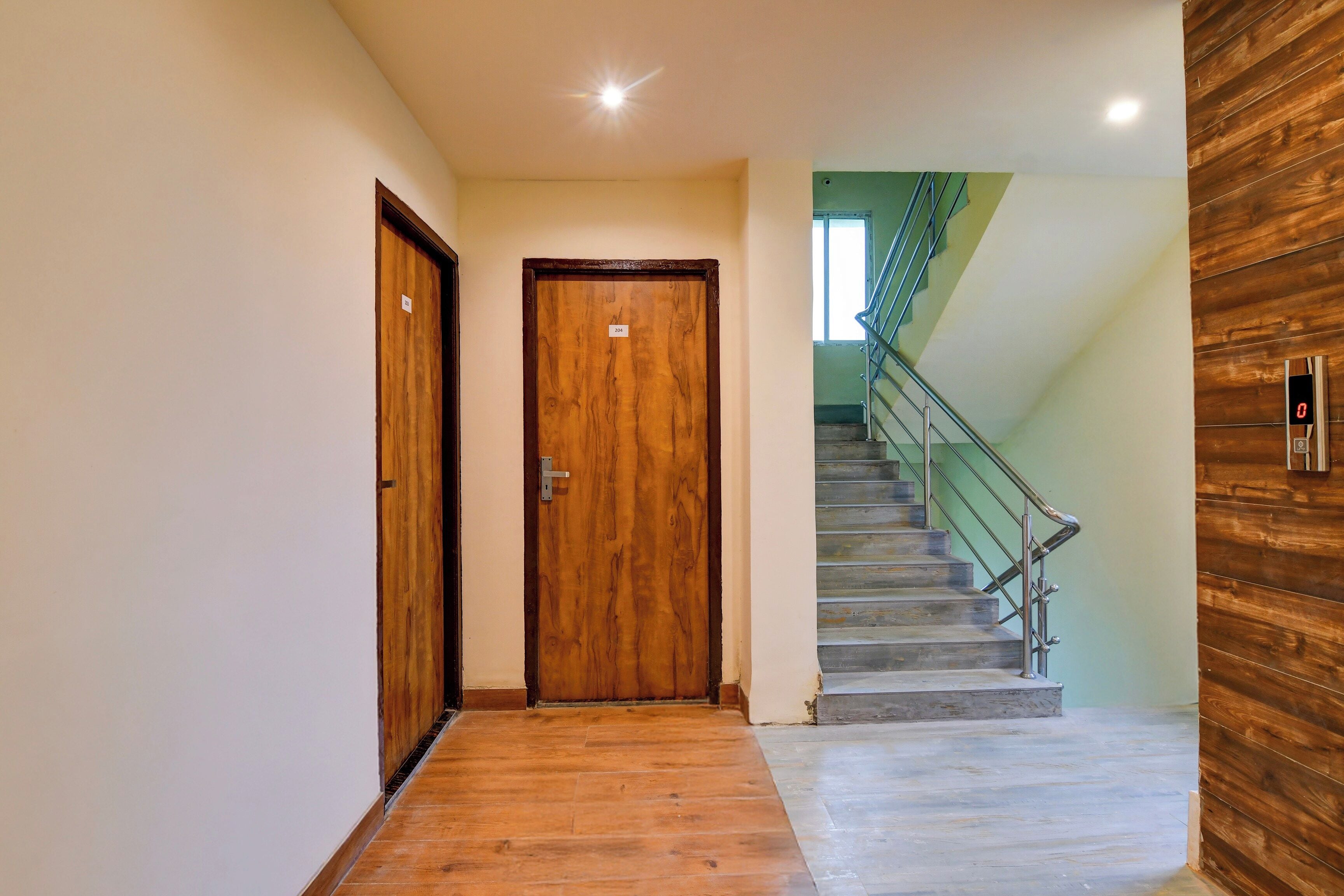 A hallway with wooden doors, a staircase with metal railings, and a wooden wall.
