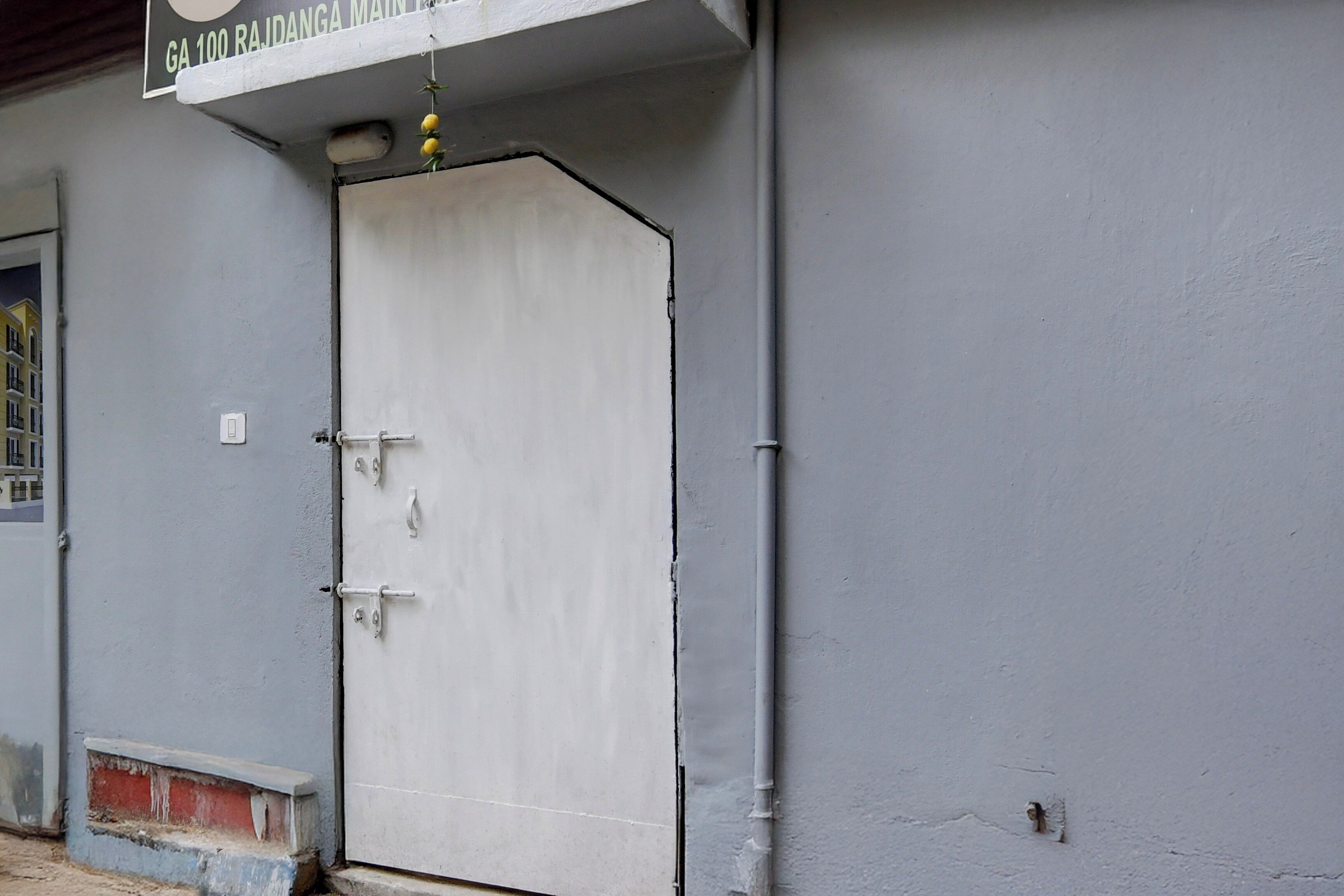 A white door with a metal handle and a latch, a small window with a metal frame, and a sign above the door with text.