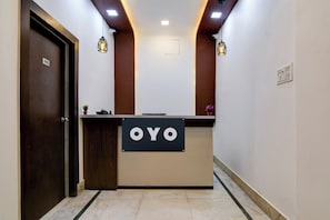 Ein Empfangsschalter mit einem Schild, auf dem 'OYO' steht, in einer modernen Hotelhalle.
