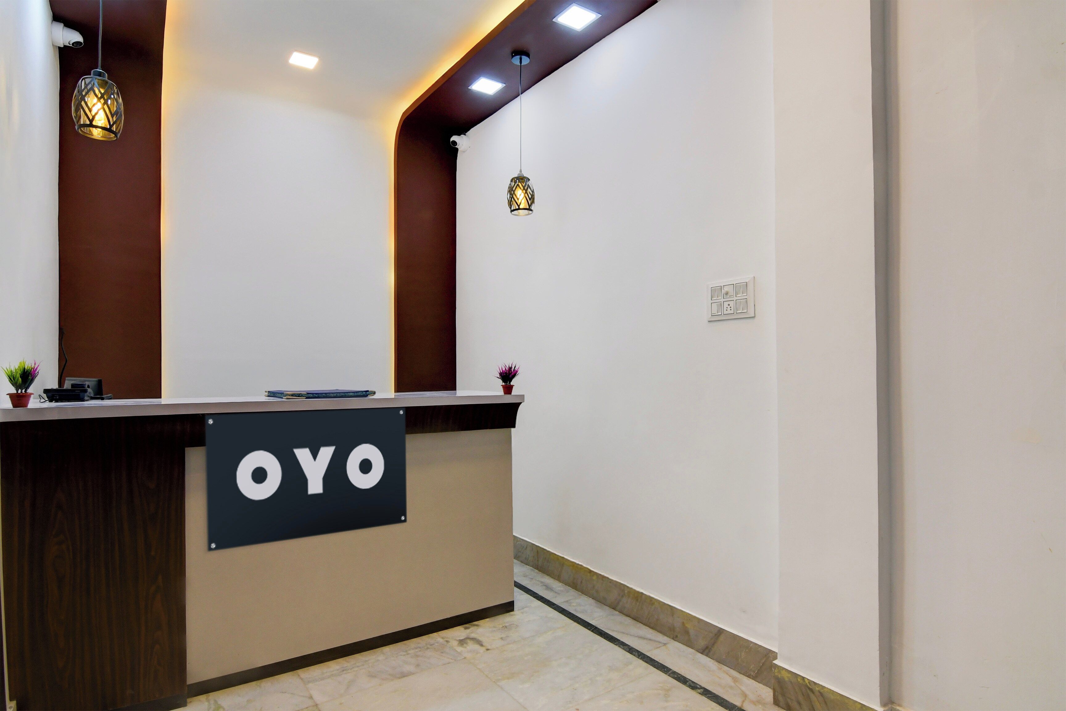 A reception desk with a sign reading 'OYO' and a potted plant on it.